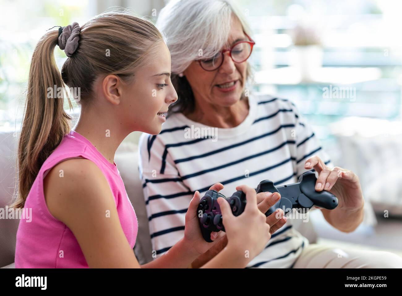 Grandmother and granddaughter talking to each other holding joysticks at home Stock Photo