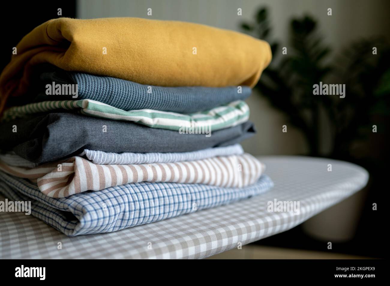 Stack of folded clothes on ironing board at home Stock Photo
