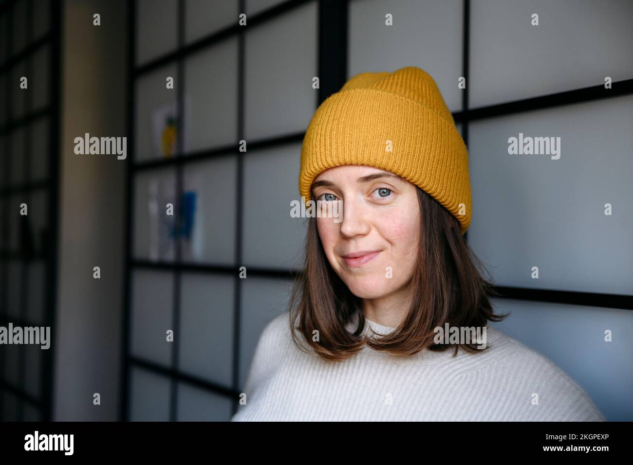 Smiling woman wearing knit hat at home Stock Photo
