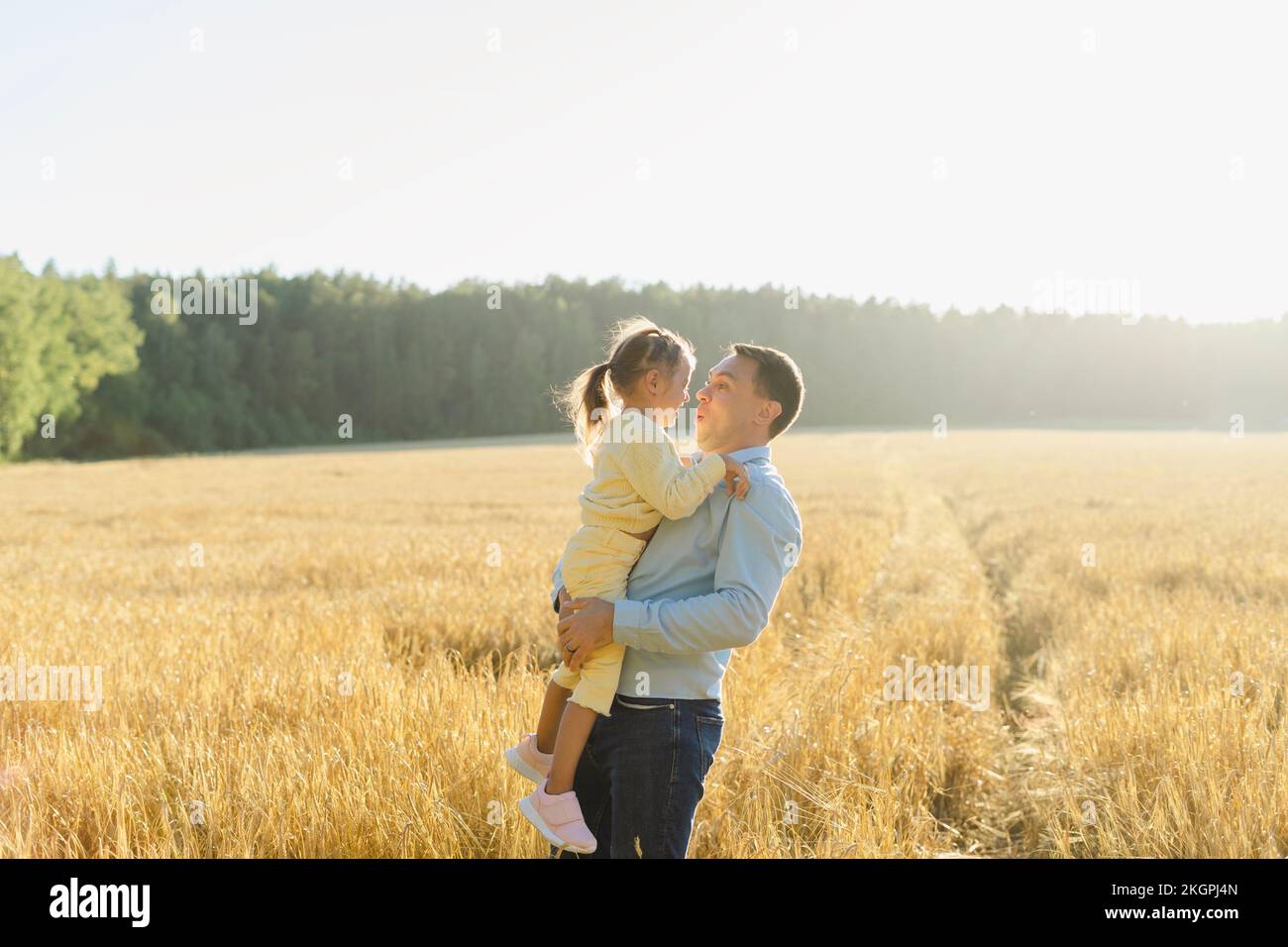 Father carrying daughter in field on sunny day Stock Photo
