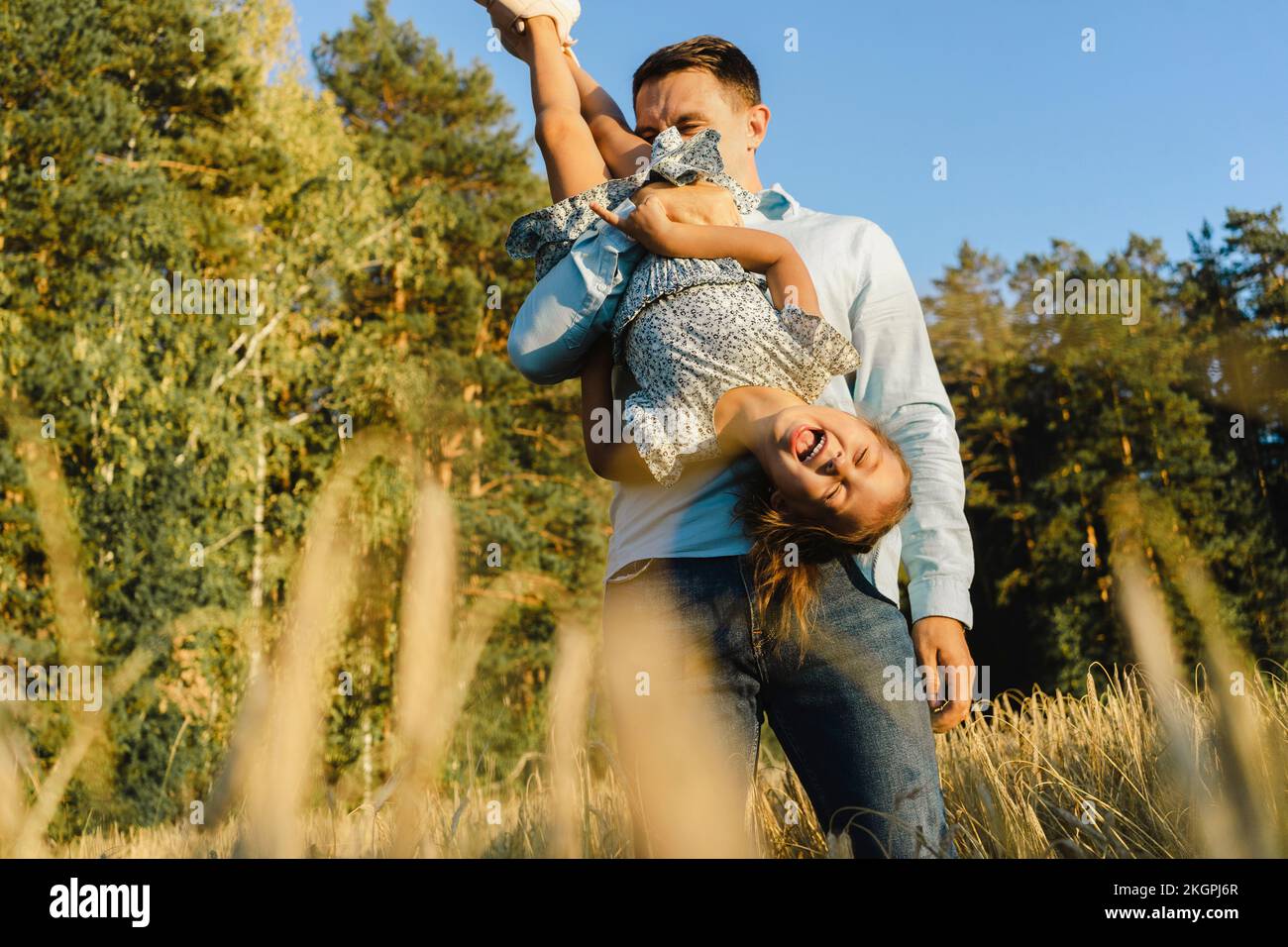 Happy father having fun with daughter at field Stock Photo
