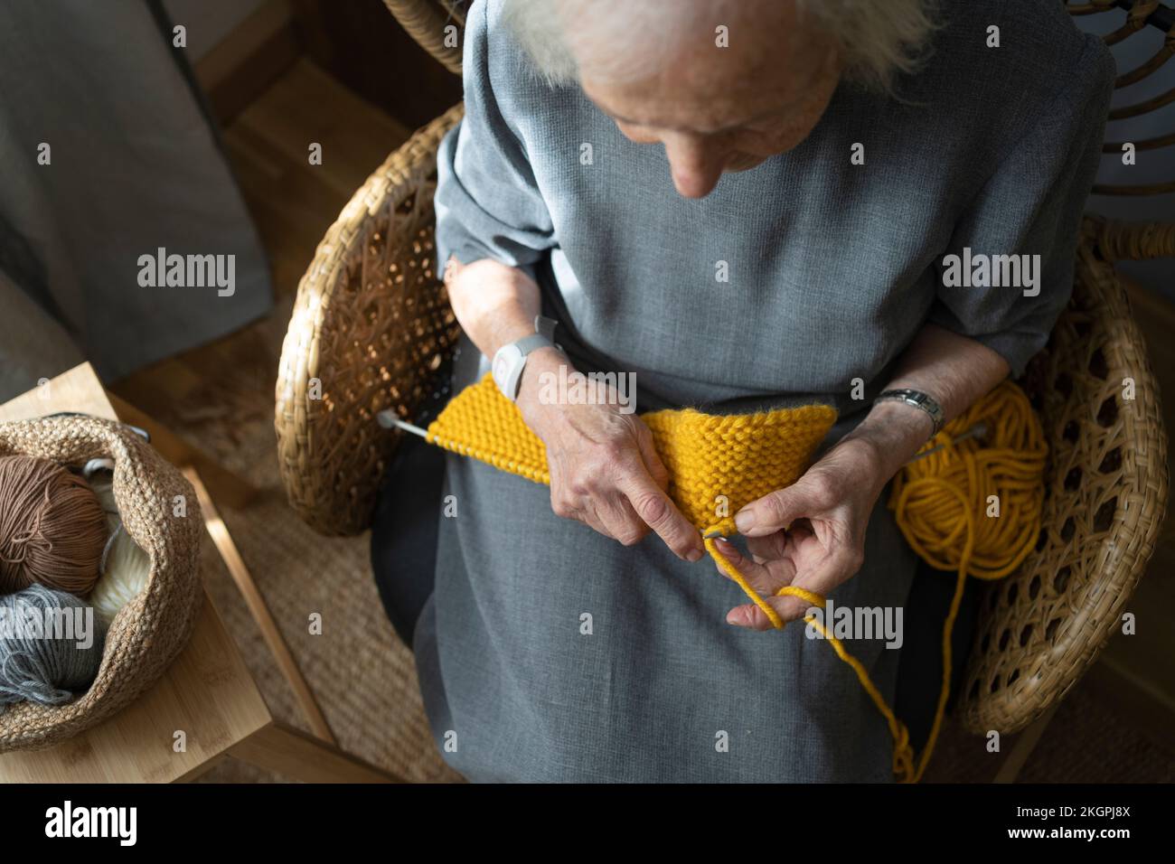 Senior woman knitting on chair at home Stock Photo - Alamy