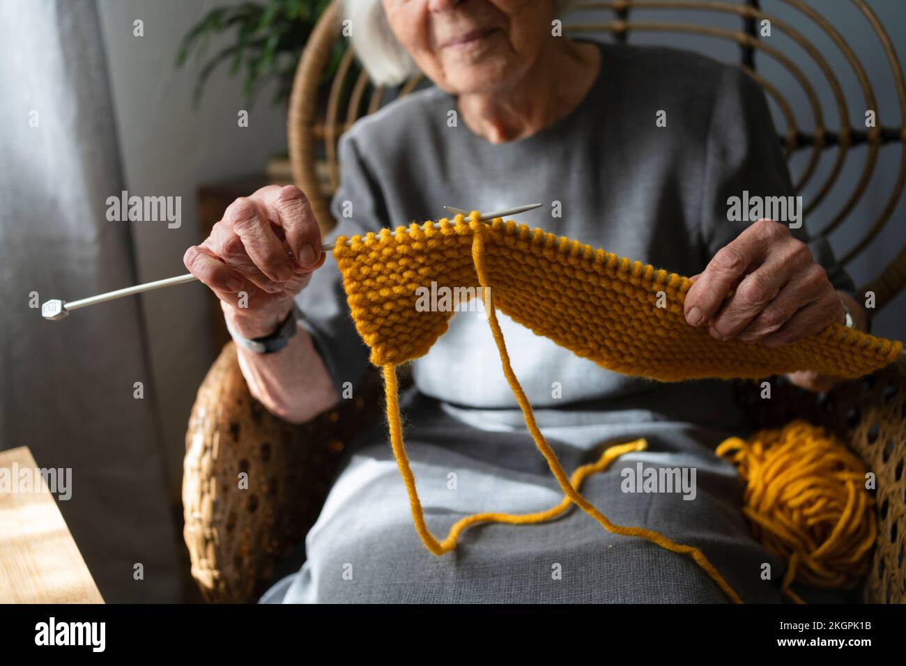 Hands of senior woman knitting scarf at home Stock Photo