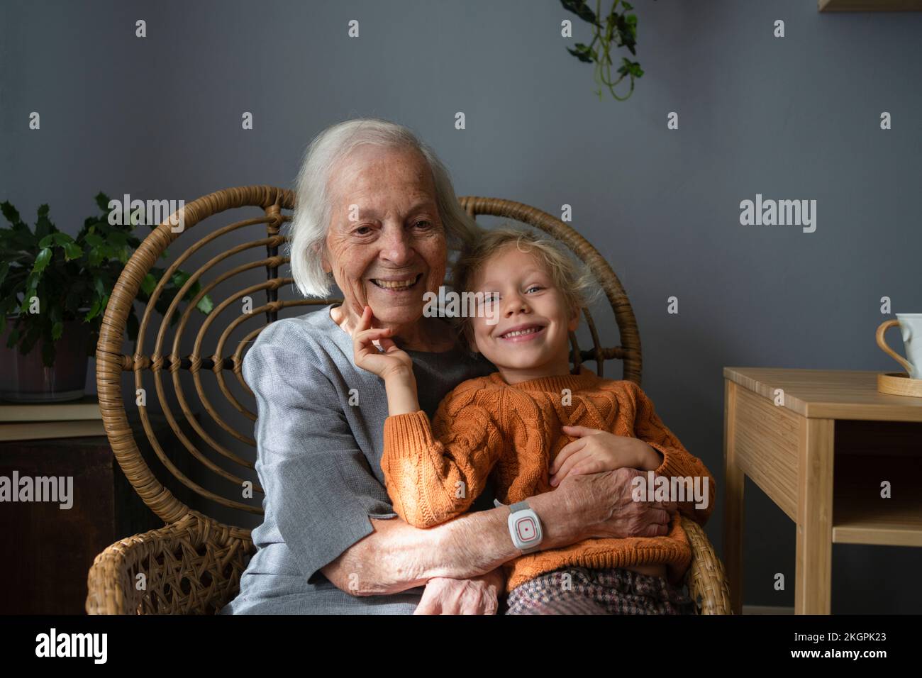 Happy grandmother embracing granddaughter on chair at home Stock Photo