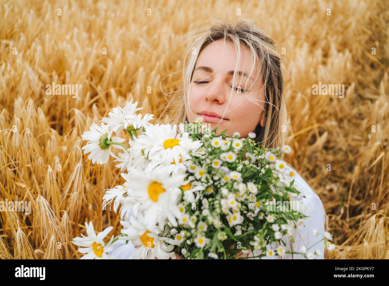 Smiling woman with eyes closed holding bunch of daises at field Stock ...