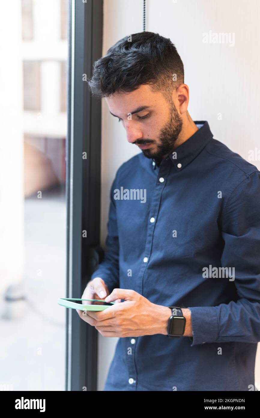 Young businessman using smart phone by window Stock Photo