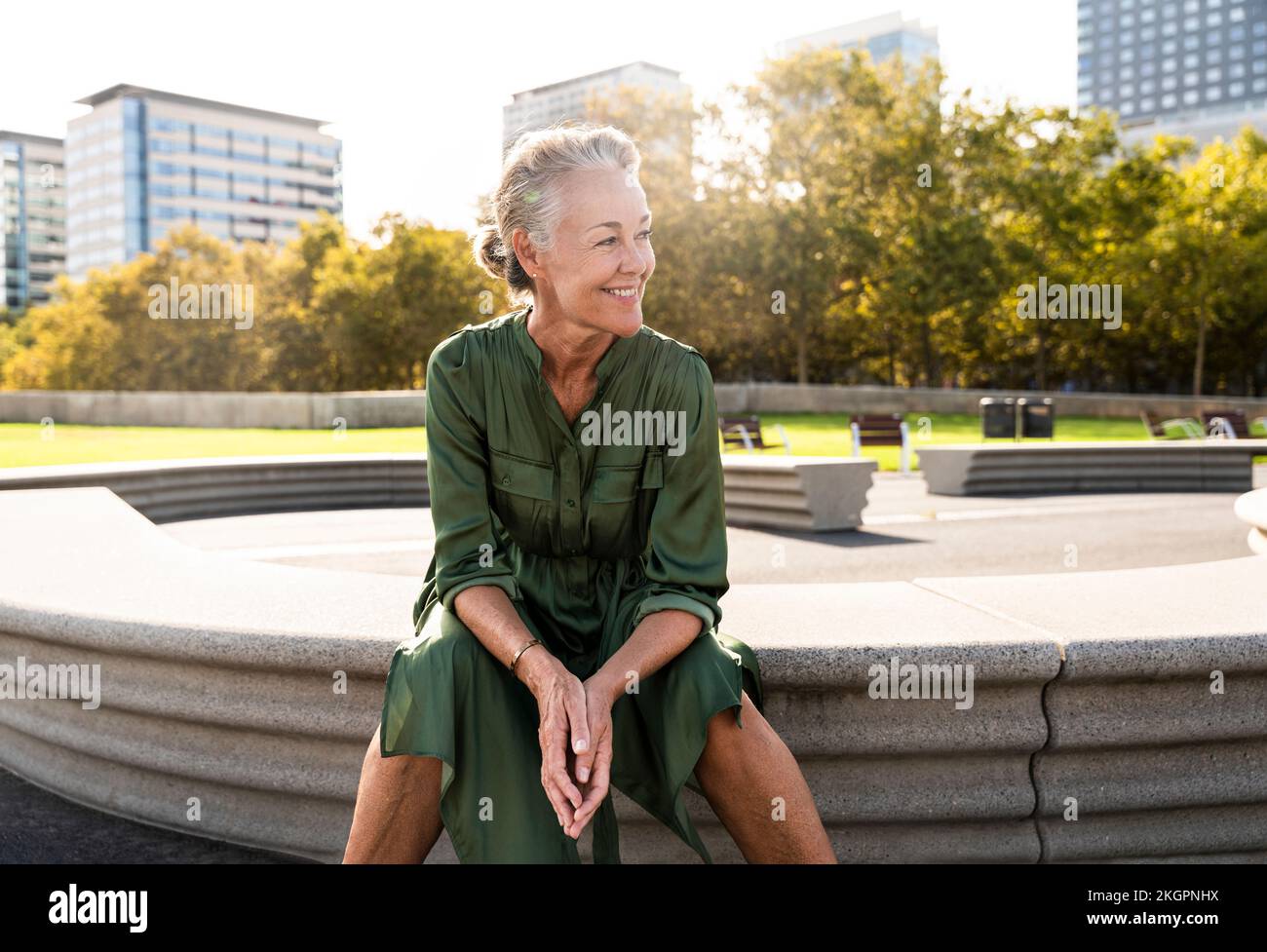 Smiling mature woman sitting on bench in park Stock Photo - Alamy