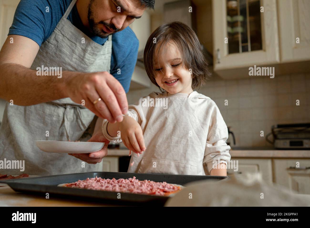 Father with son making pizza in kitchen at home Stock Photo