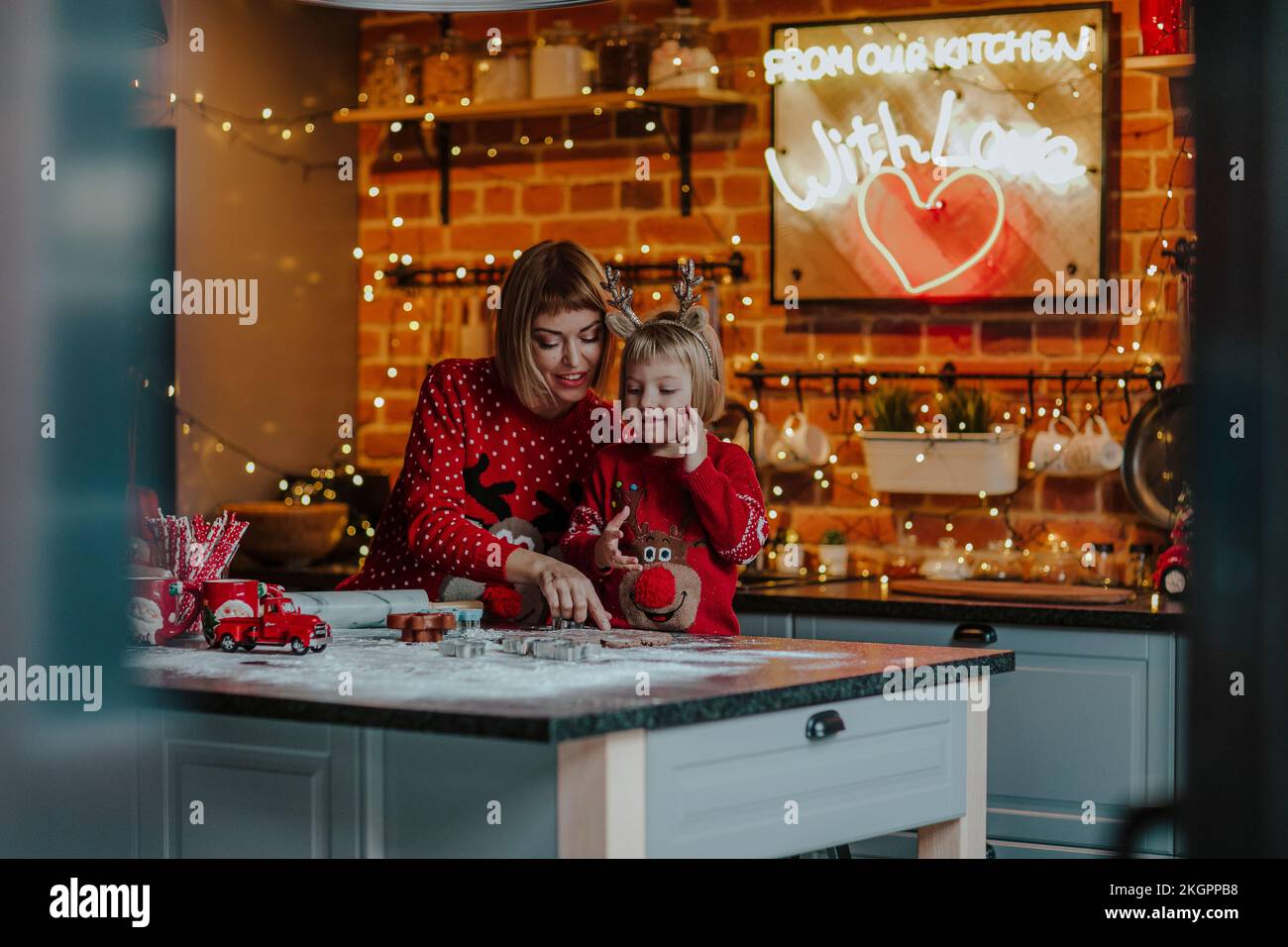 Mother and daughter cooking together on kitchen island in Christmas Stock Photo