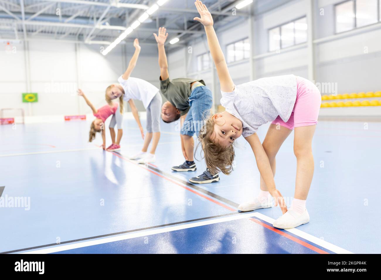 Elementary students doing stretching exercise with each other at school
