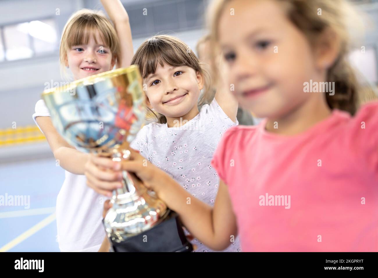 Schoolgirls celebrating victory with trophy at school sports court Stock Photo