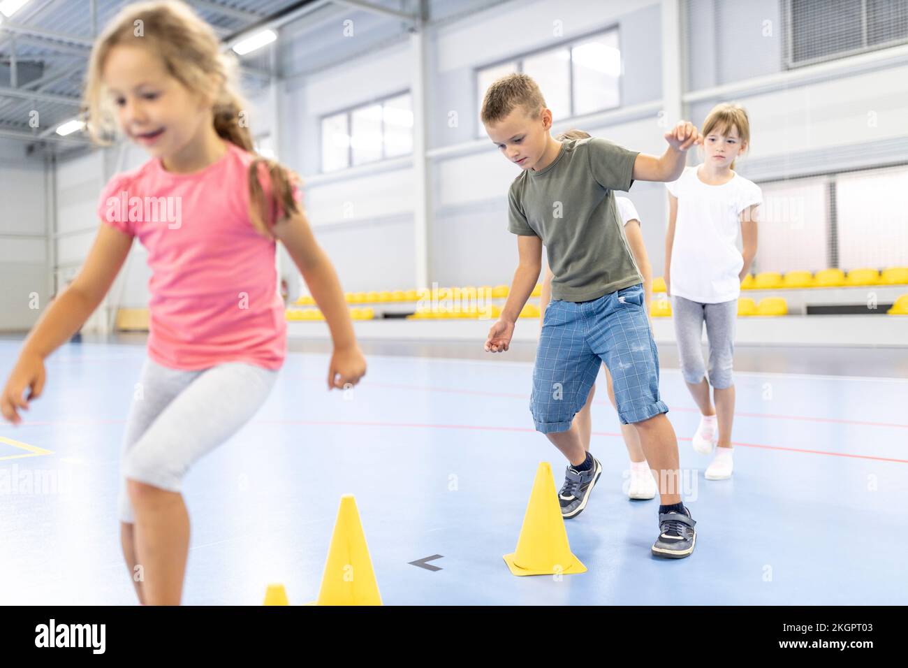 Students doing warm up exercise with cones at school sports court Stock