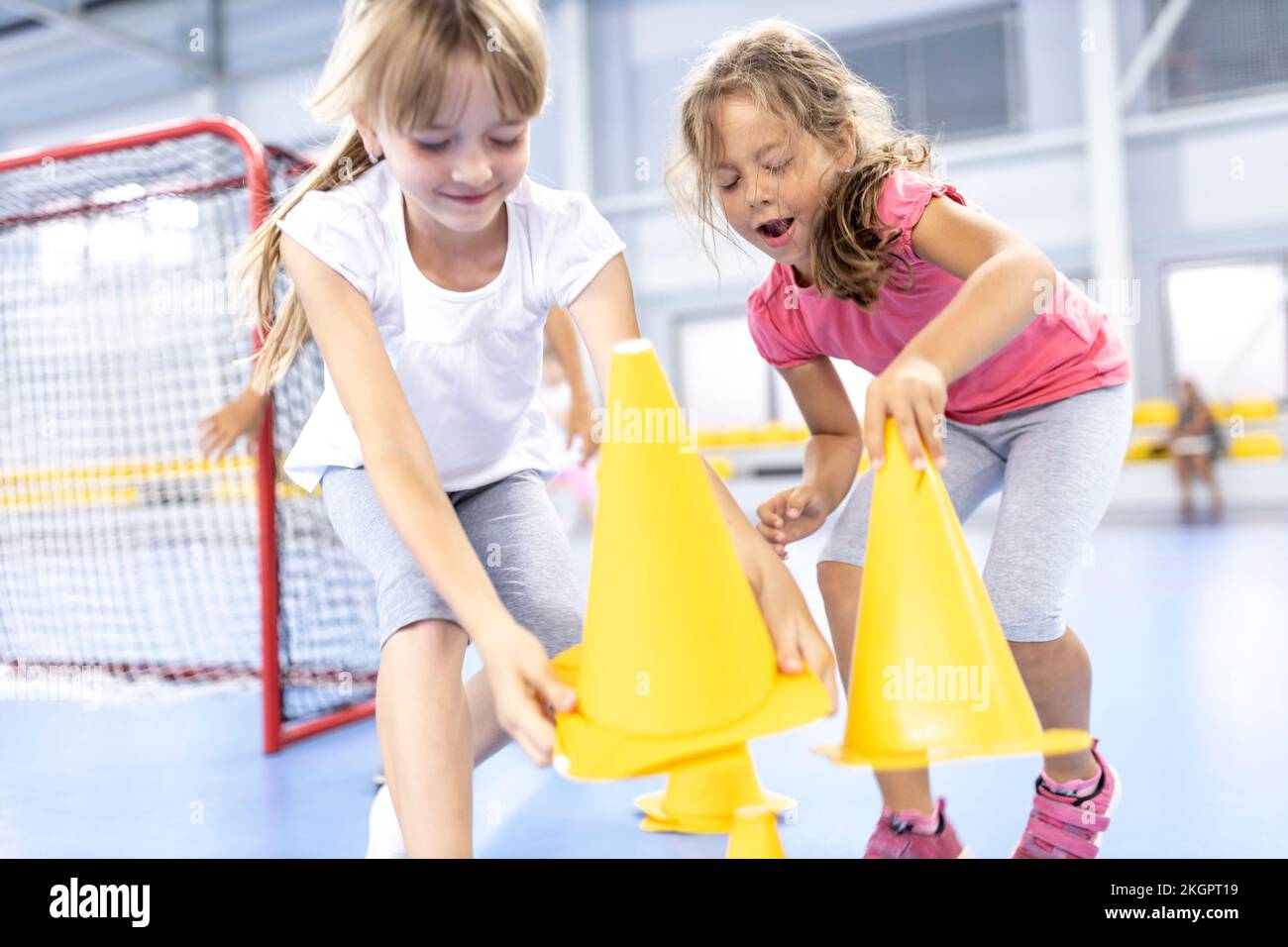 Playful girls picking up cones at school sports court Stock Photo Alamy