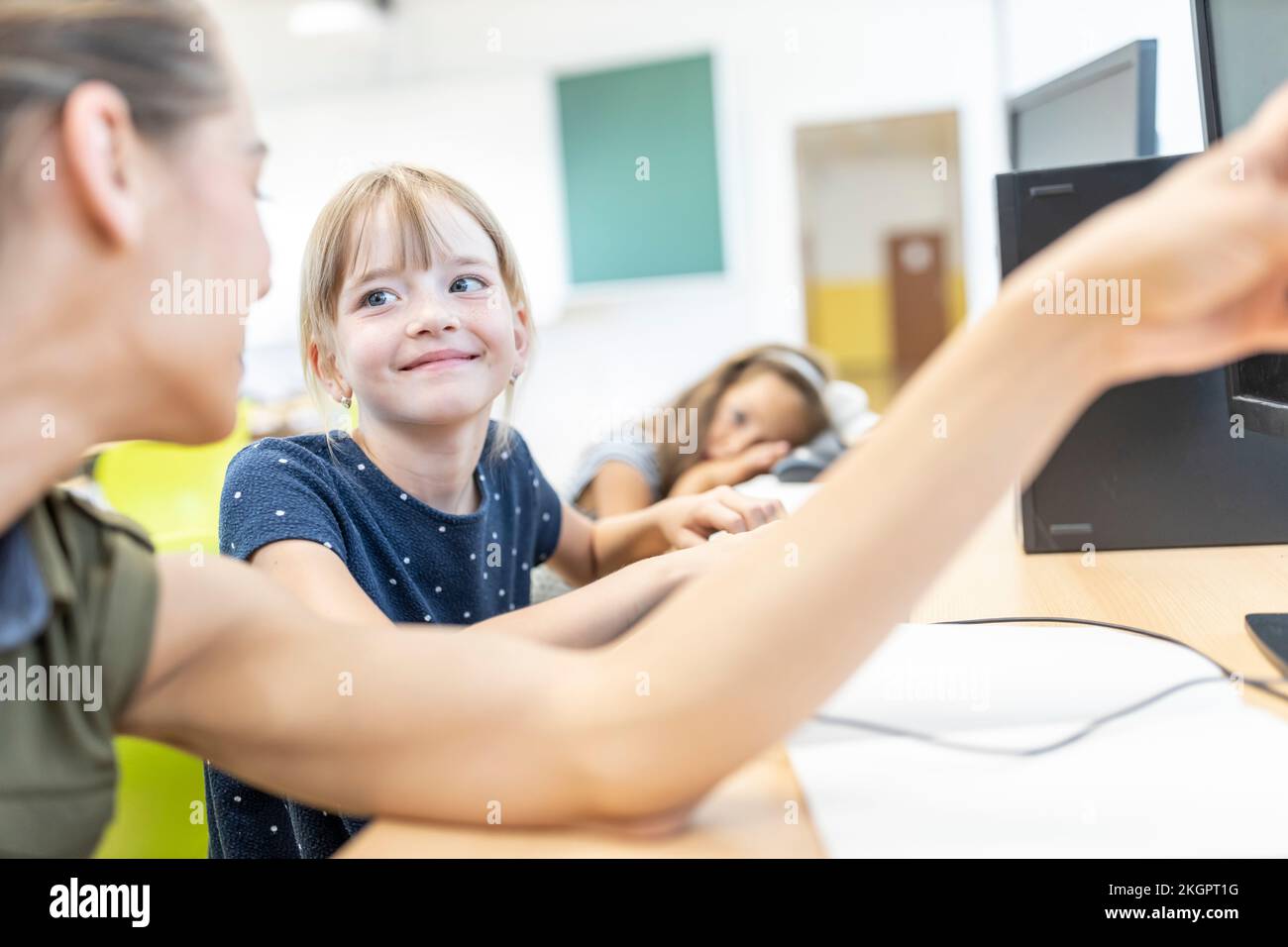 Smiling girl looking at teacher teaching in E-learning class Stock Photo
