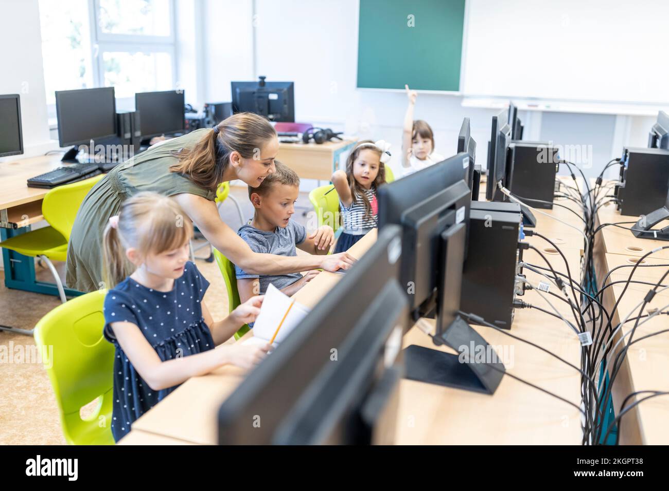 Teacher helping students studying through E-learning at school Stock Photo