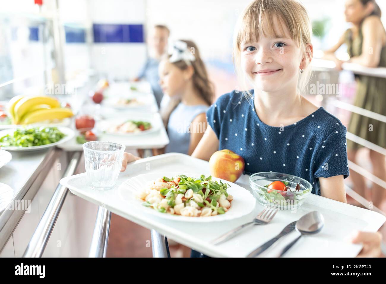 Smiling girl holding food tray in school cafeteria Stock Photo