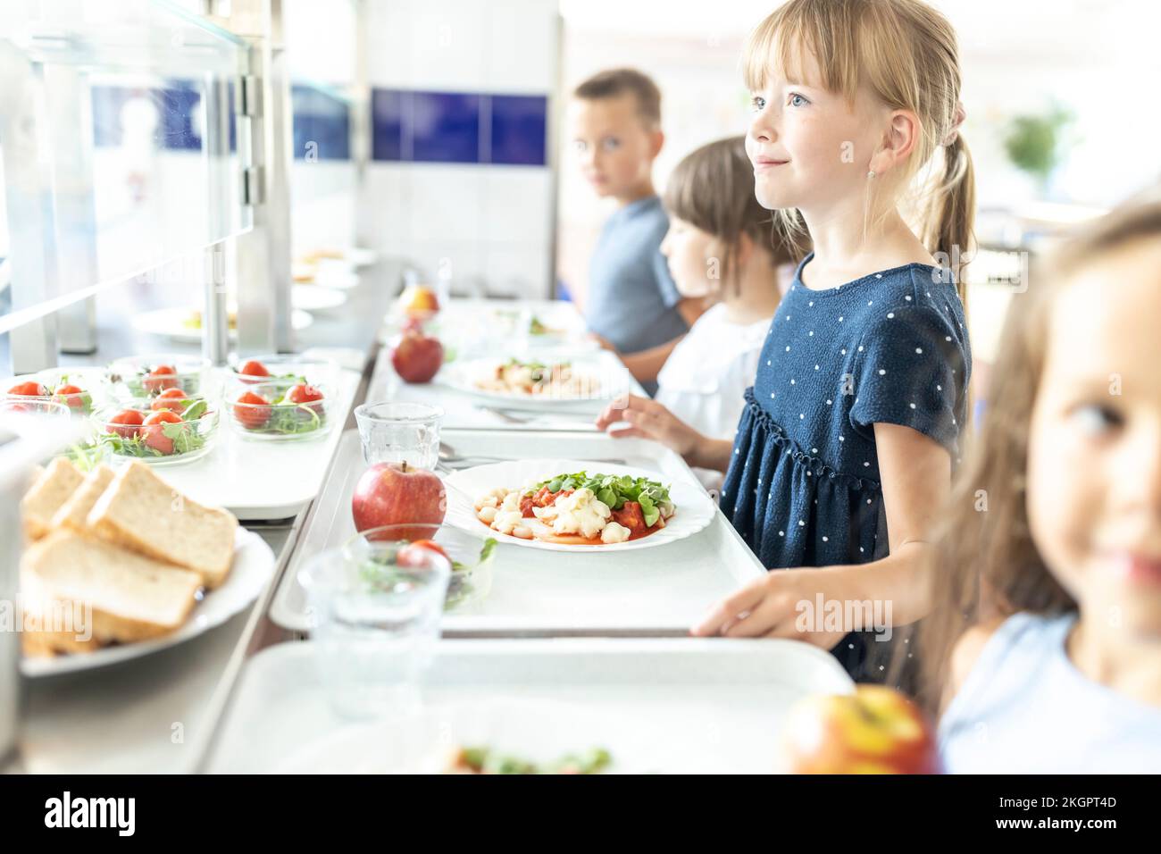 Girl with blond hair holding lunch tray at school cafeteria Stock Photo