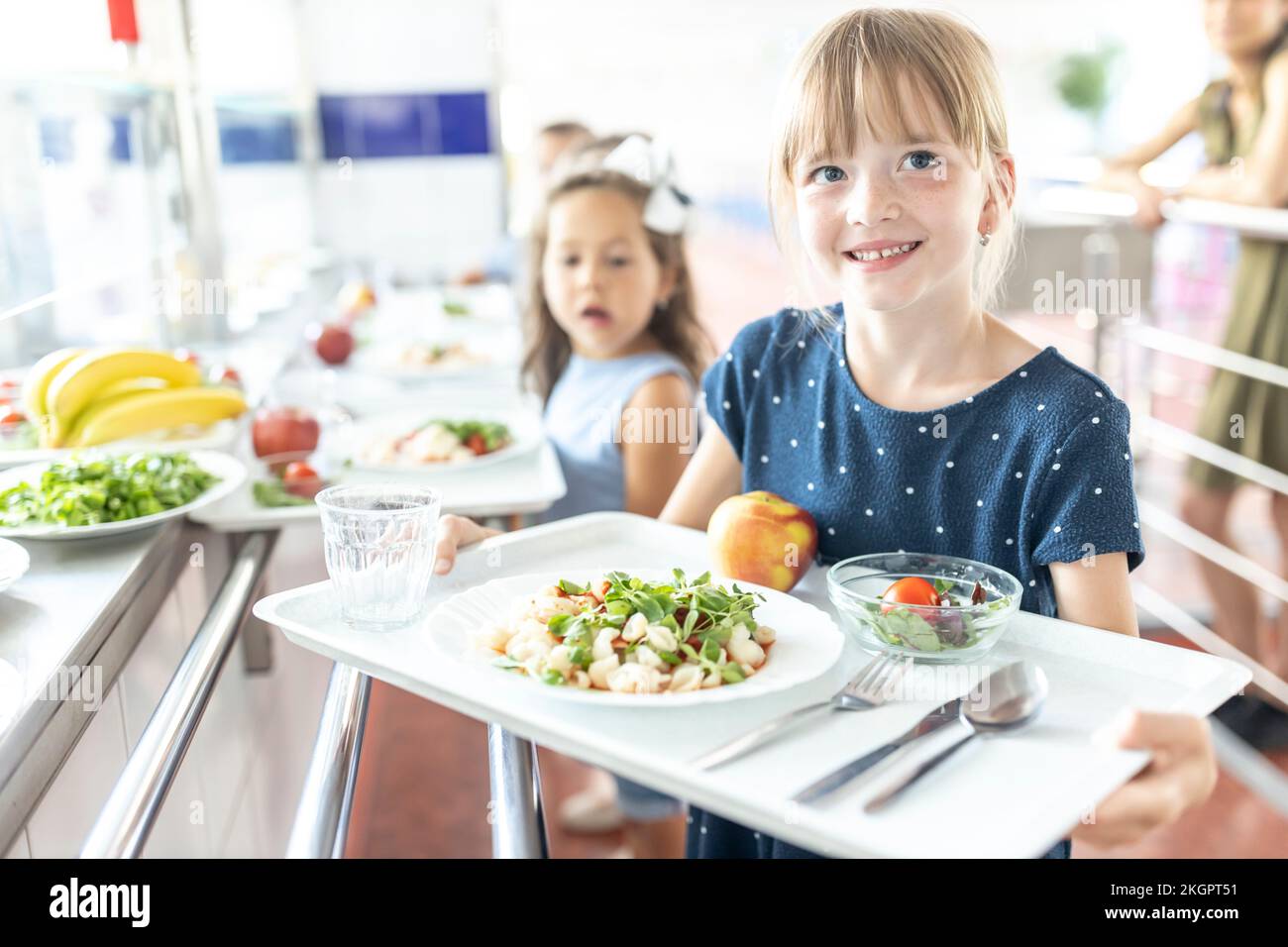 Smiling girl holding tray at lunch break in school cafeteria Stock Photo