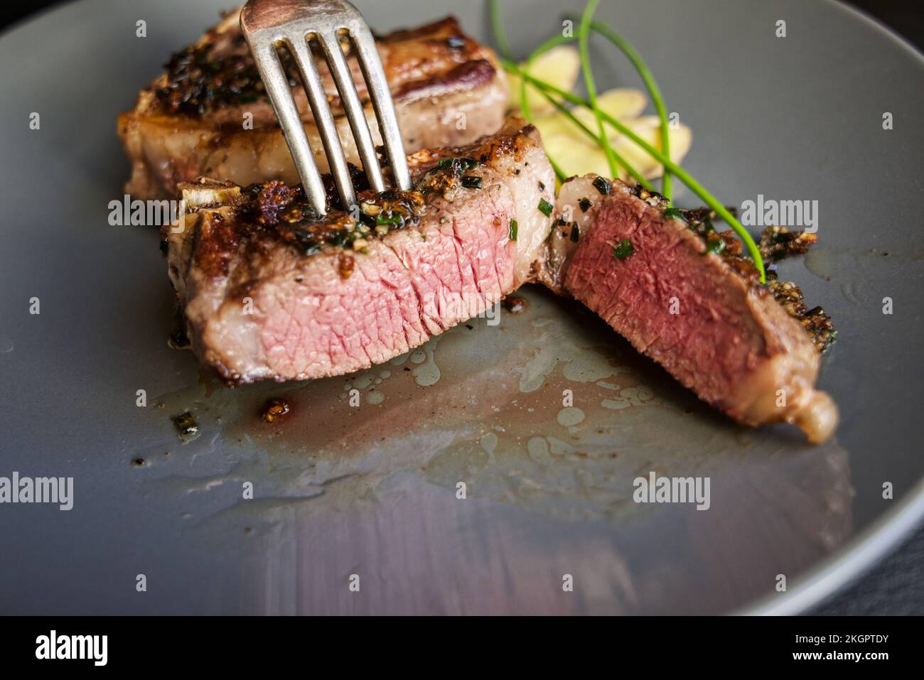 Cooked lamb chops, displayed on a plate with a classy herb and ginger garnish. Stock Photo