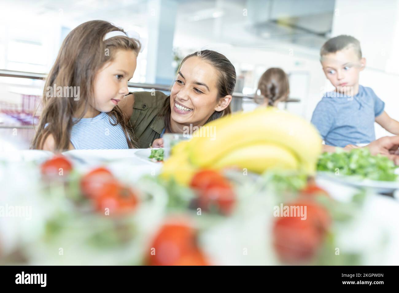 Happy teacher looking at student in school cafeteria Stock Photo