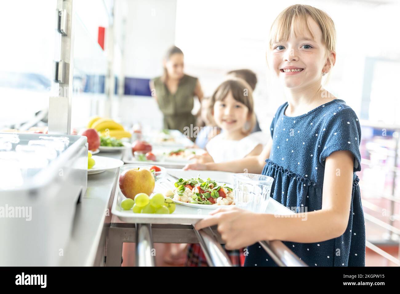 Blond smiling student with healthy meal at school cafeteria Stock Photo