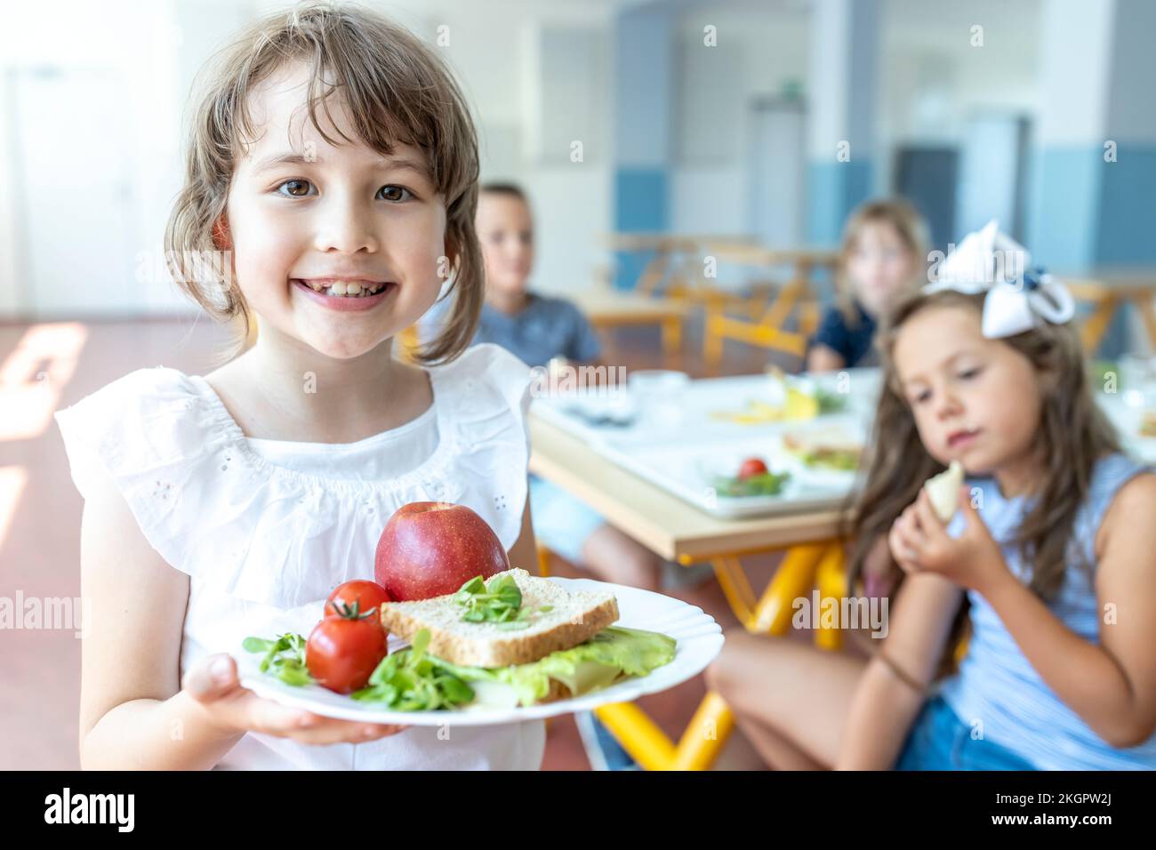 Smiling student holding healthy meal on plate standing at cafeteria Stock Photo