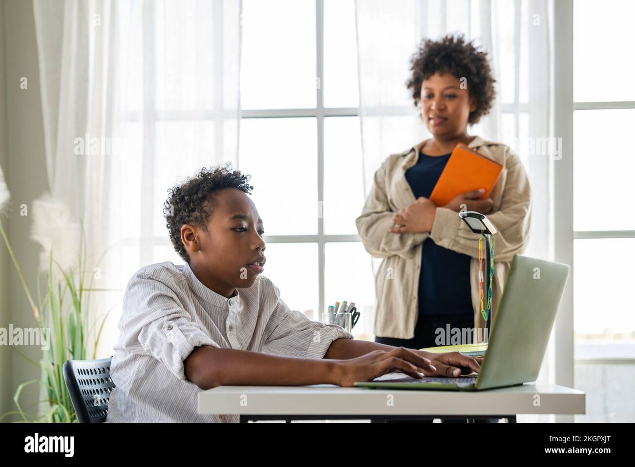 Boy e-learning on laptop by mother at home Stock Photo