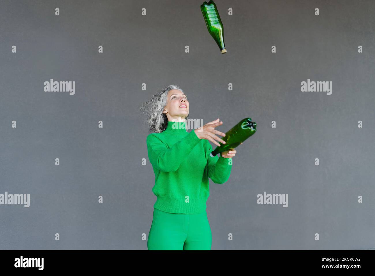 Woman throwing plastic water bottle in front of wall Stock Photo