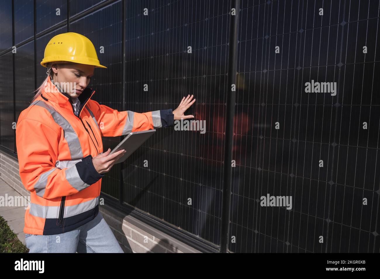 Young female engineer using tablet PC standing by solar panels Stock Photo