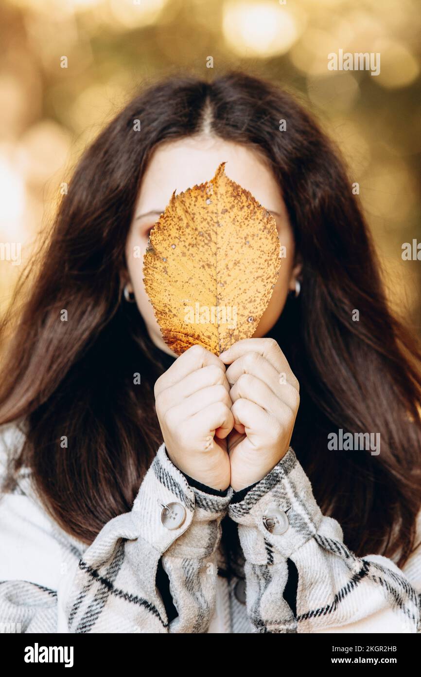 Girl covering face with yellow leaf Stock Photo
