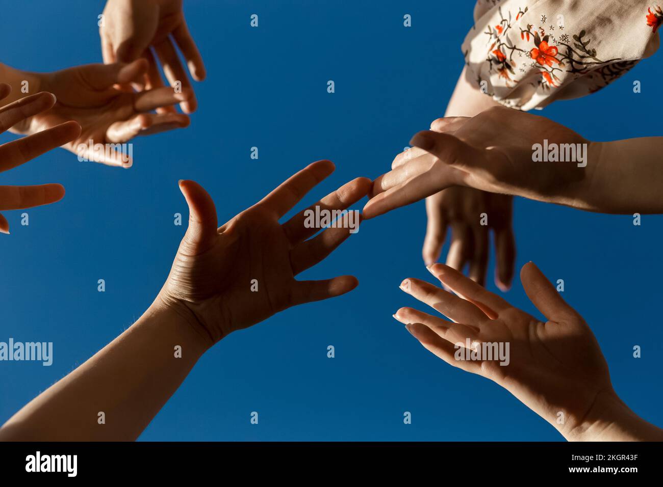 Hands of women under blue sky Stock Photo - Alamy