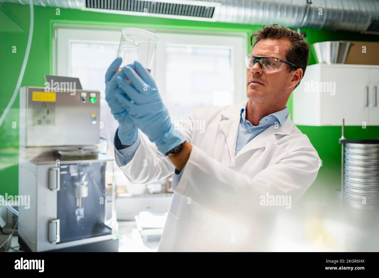 Scientist examining measuring beaker at laboratory Stock Photo