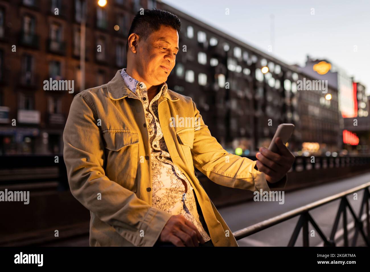 Smiling mature man using smart phone at night Stock Photo