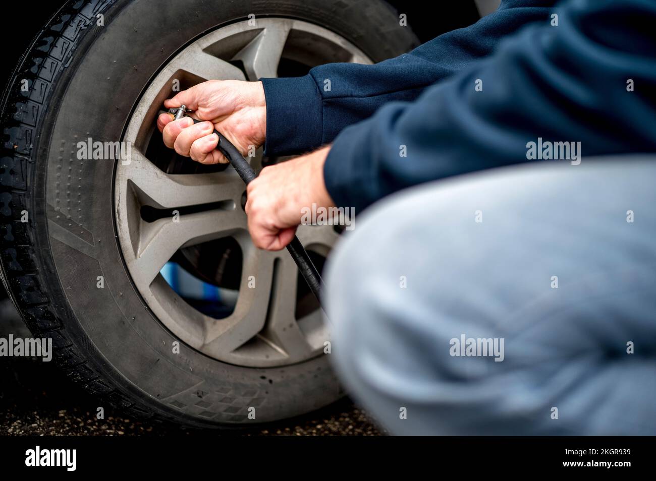 Hand's of man filling air in tire at gas station Stock Photo - Alamy