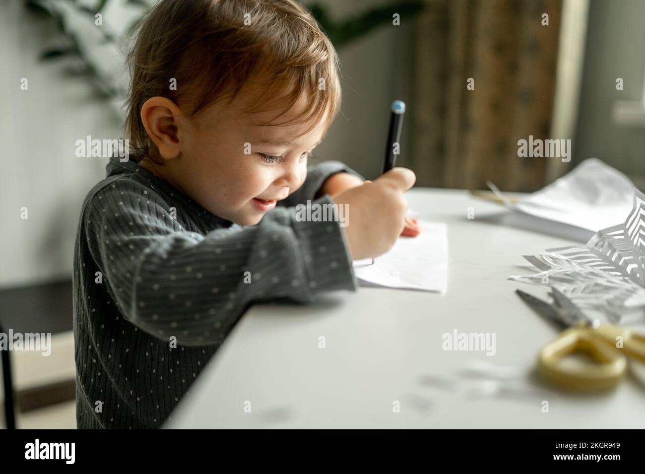 Boy drawing on paper with pencil at table in home Stock Photo