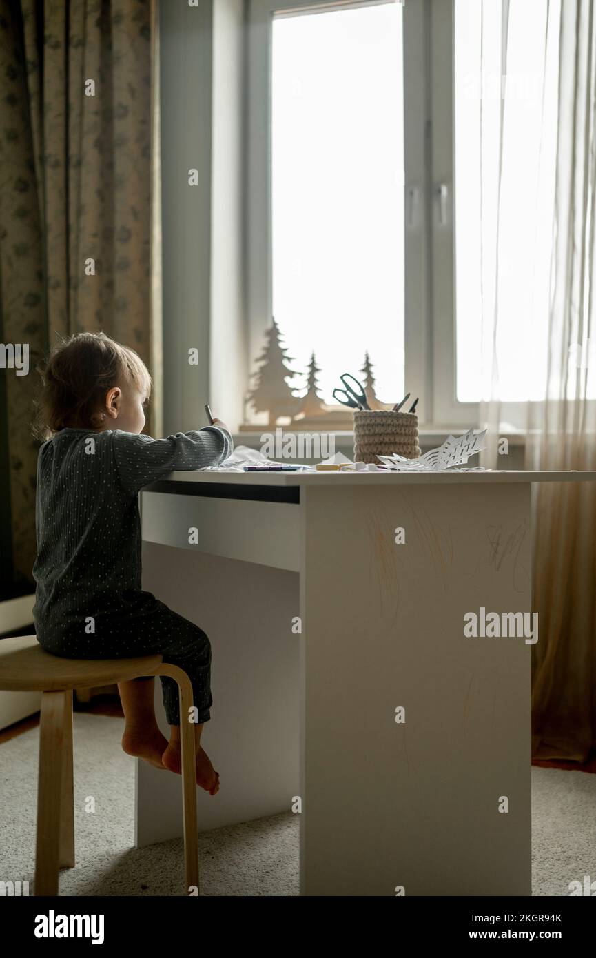 Baby boy doing drawing at table in home Stock Photo