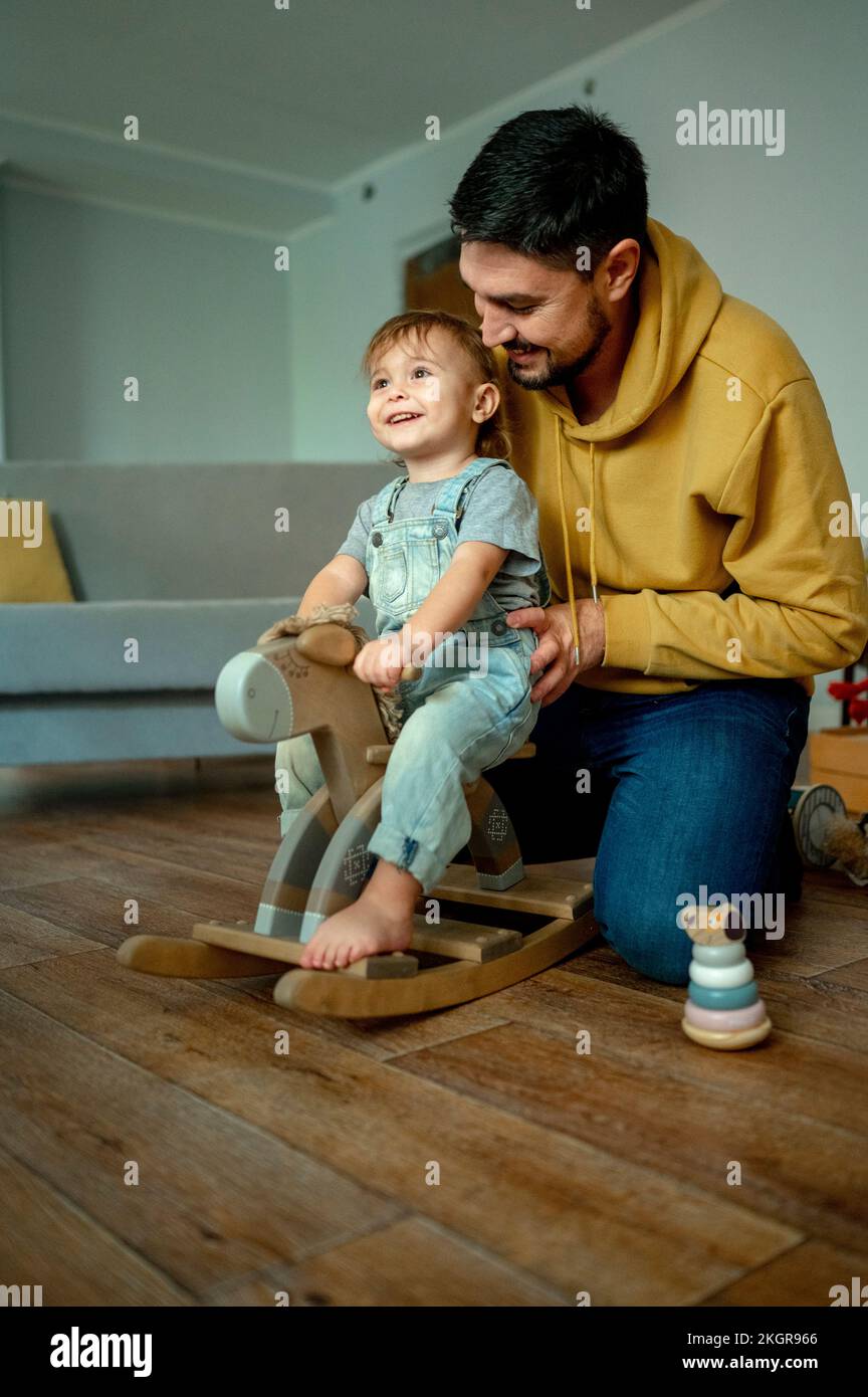 Dad Rocking Manger Happy boy with father playing on rocking horse at home Stock Photo - Alamy