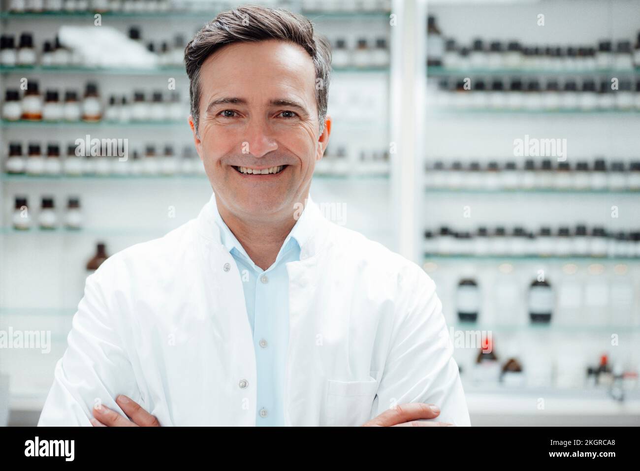 Happy pharmacist in front of medicines on shelf at store Stock Photo