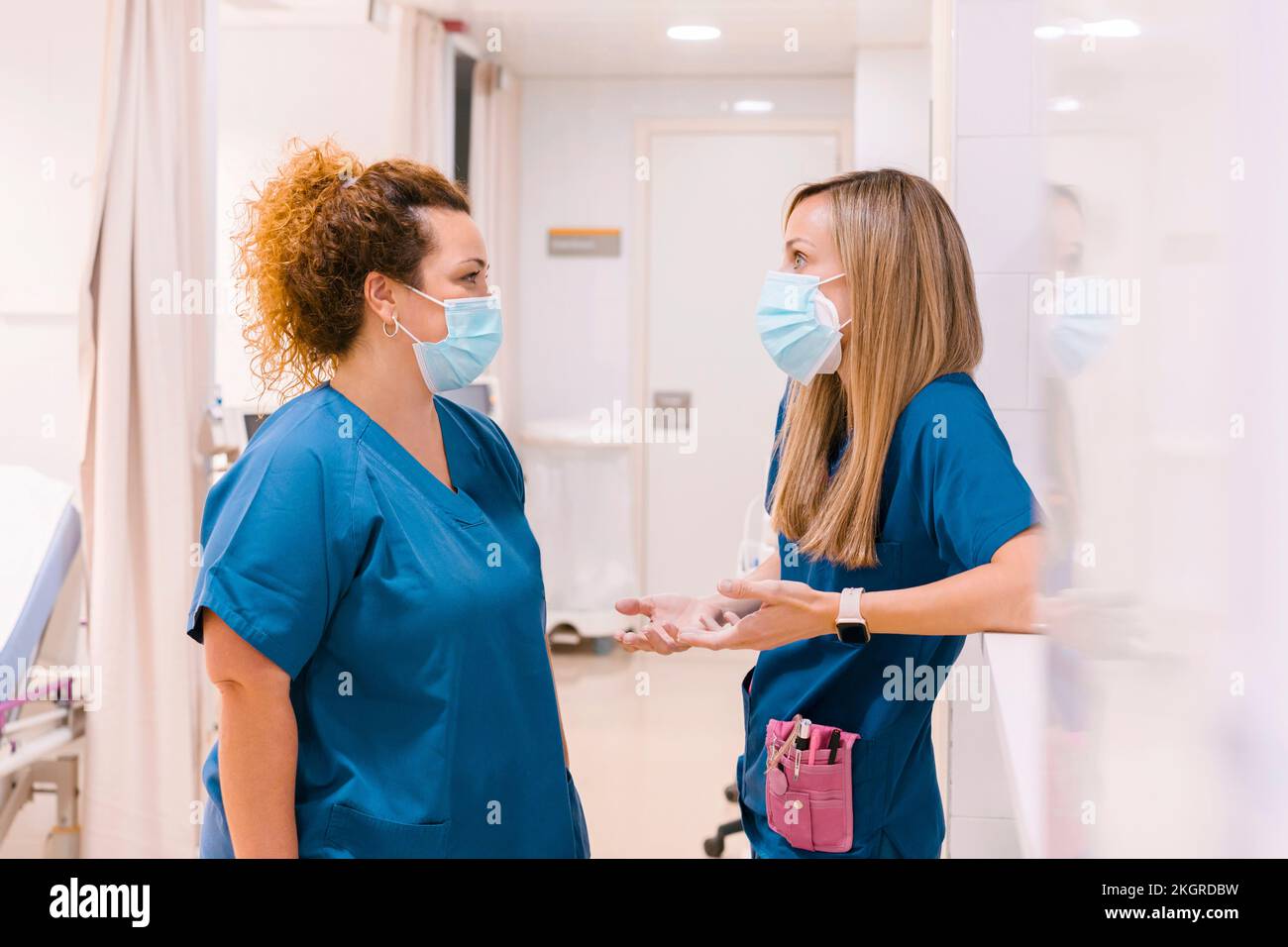 Nurses wearing masks talking with each other at hospital Stock Photo