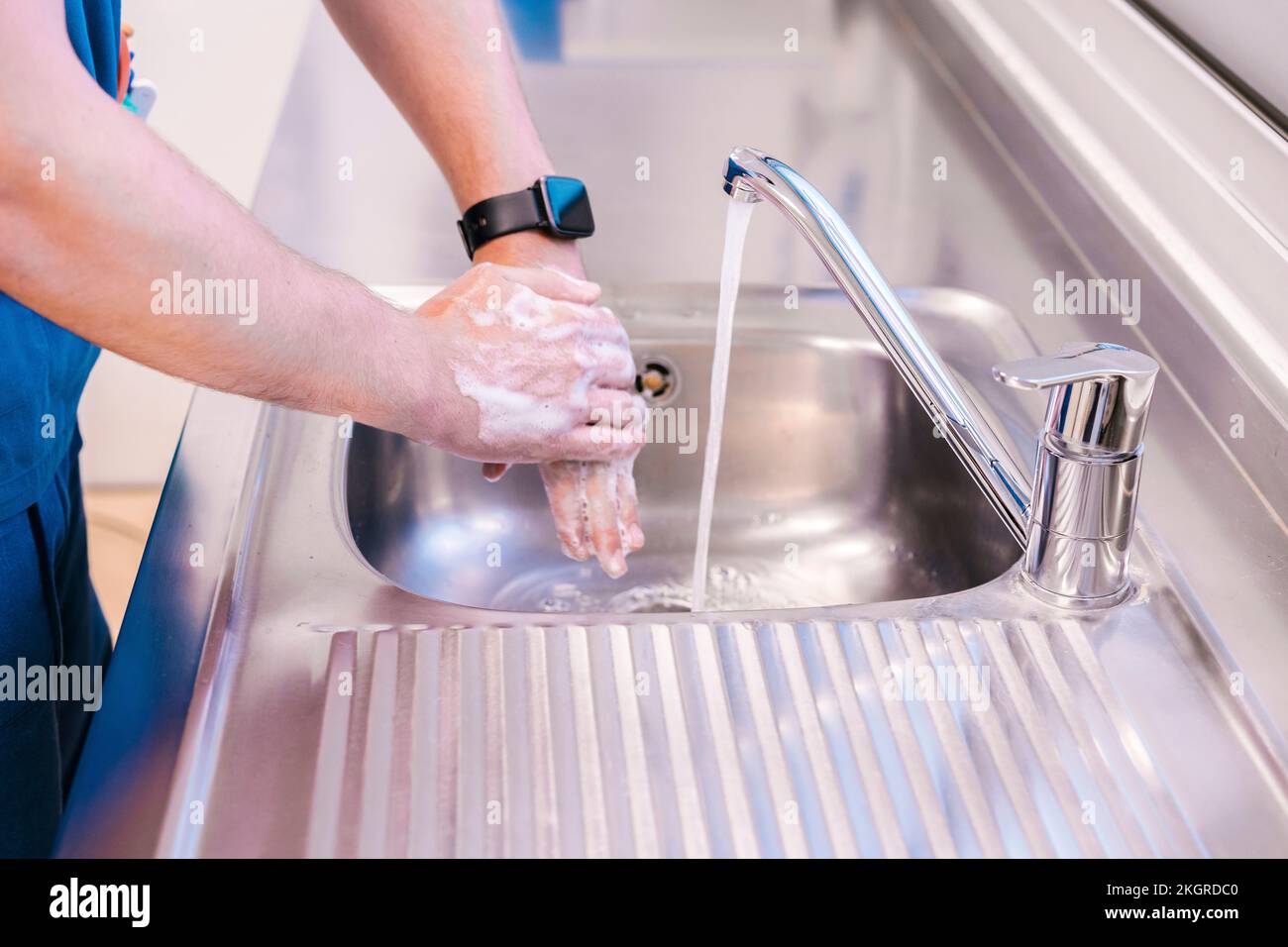 Doctor washing hands with water in sink at hospital Stock Photo