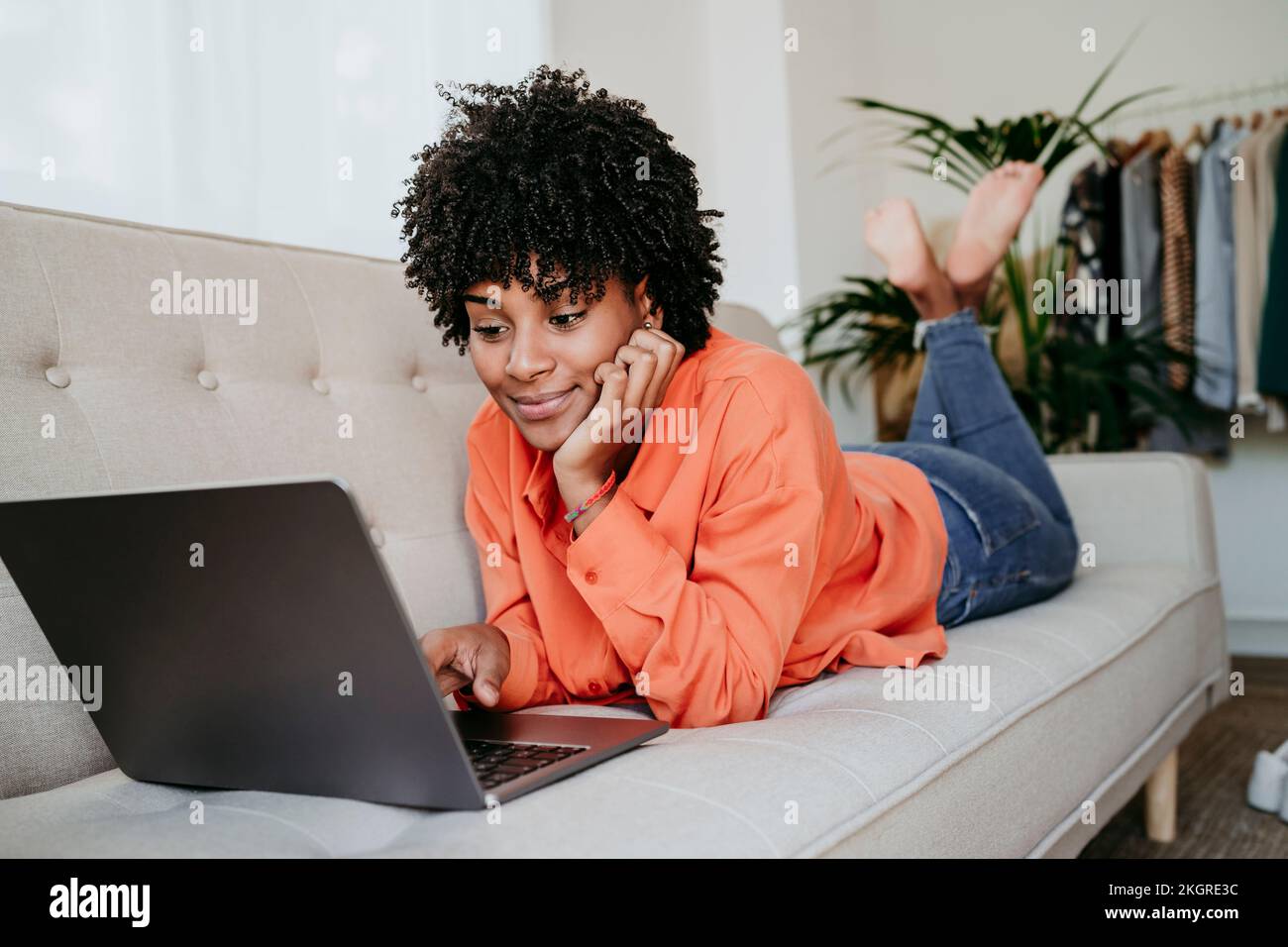 Freelancer lying on sofa and using laptop at home office Stock Photo