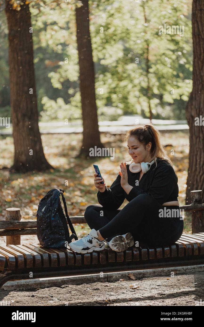 Smiling woman having video call through smart phone on bench in park Stock Photo