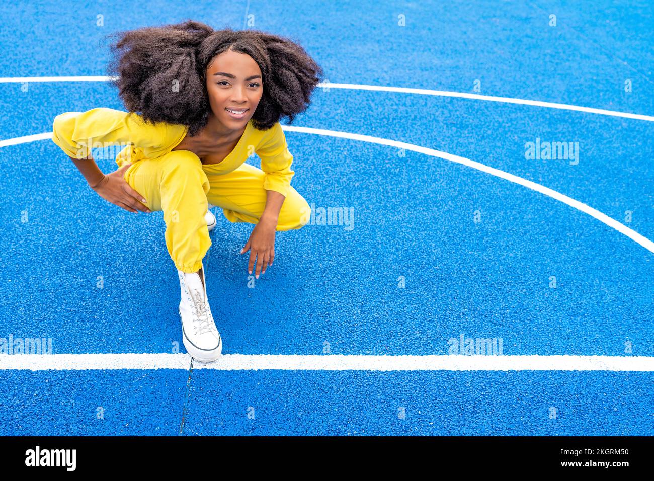 Smiling young woman crouching on basketball court Stock Photo Alamy