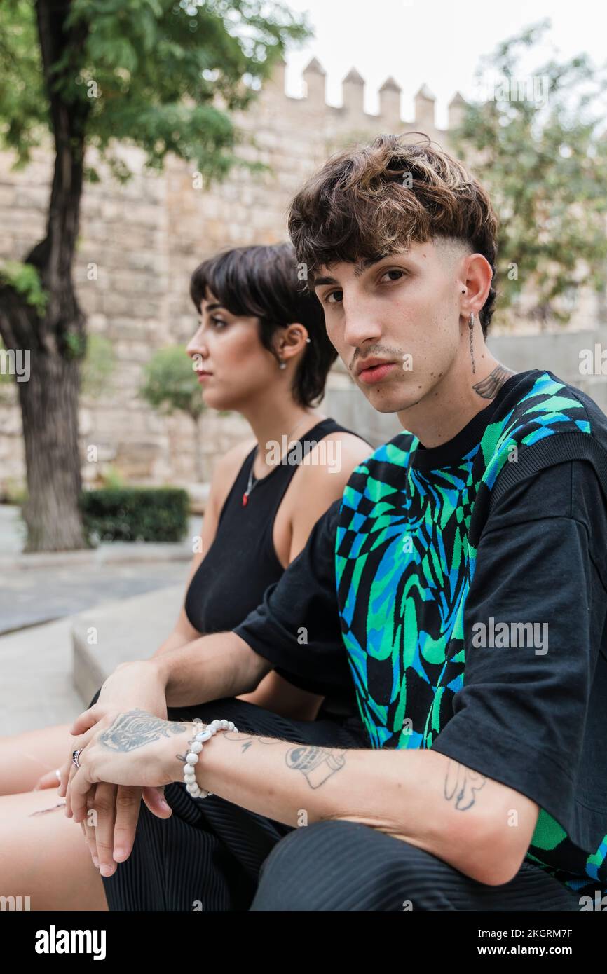 Young man with tattoo sitting by girlfriend on staircase Stock Photo