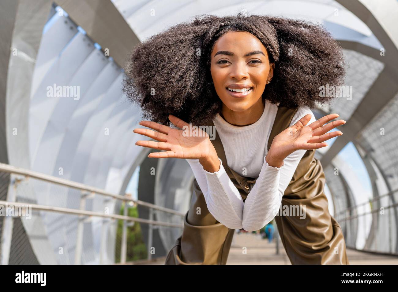 Smiling woman with Afro hair bending on bridge Stock Photo