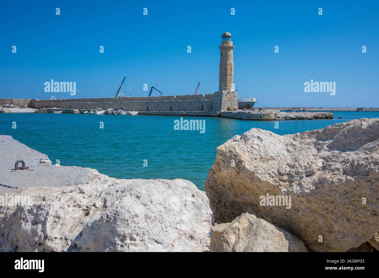 Greece, Crete, Rethymno, Lighthouse with coastal boulders in foreground Stock Photo