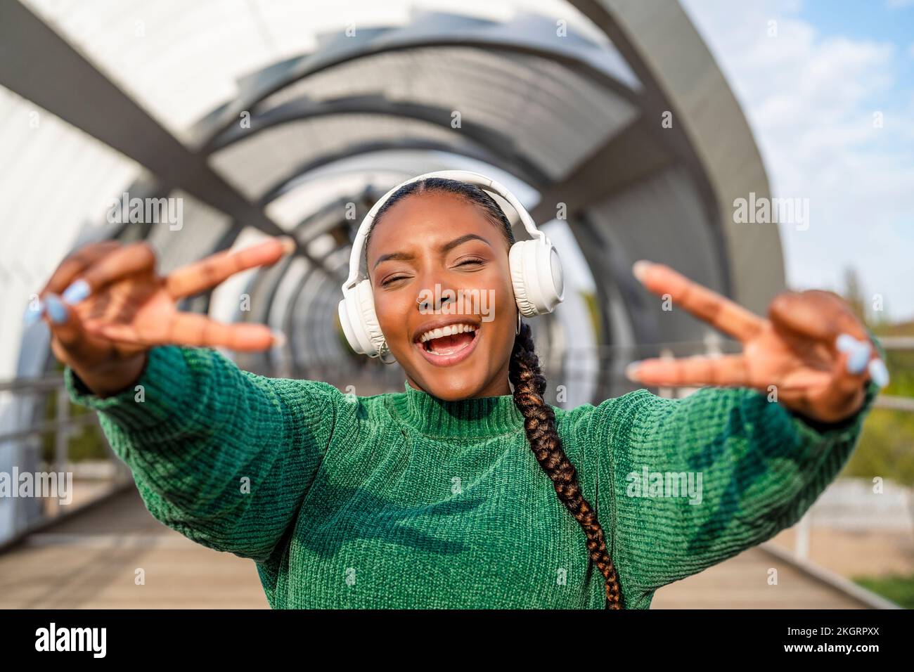 Happy young woman listening to music through wireless headphones and ...