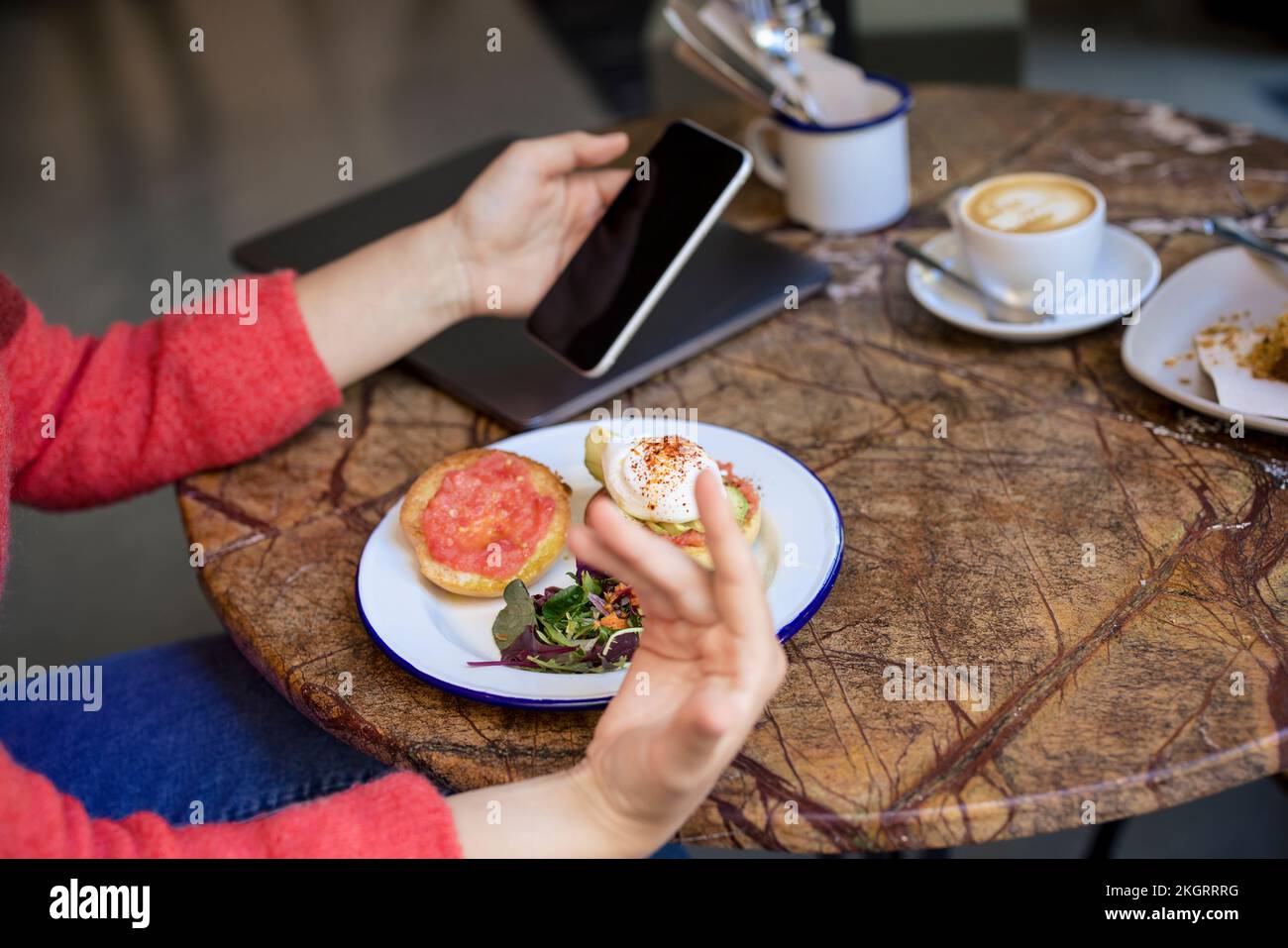 Freelancer using smart phone at table in cafe Stock Photo