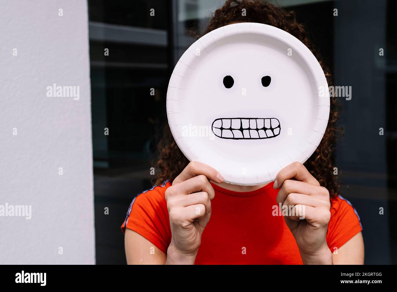 Young woman holding happy emoticon plate over face Stock Photo