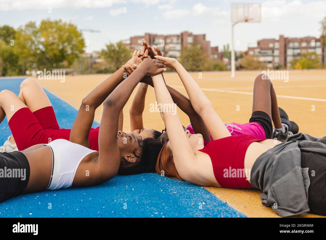 Young women lying down with hands raised in sports court Stock Photo